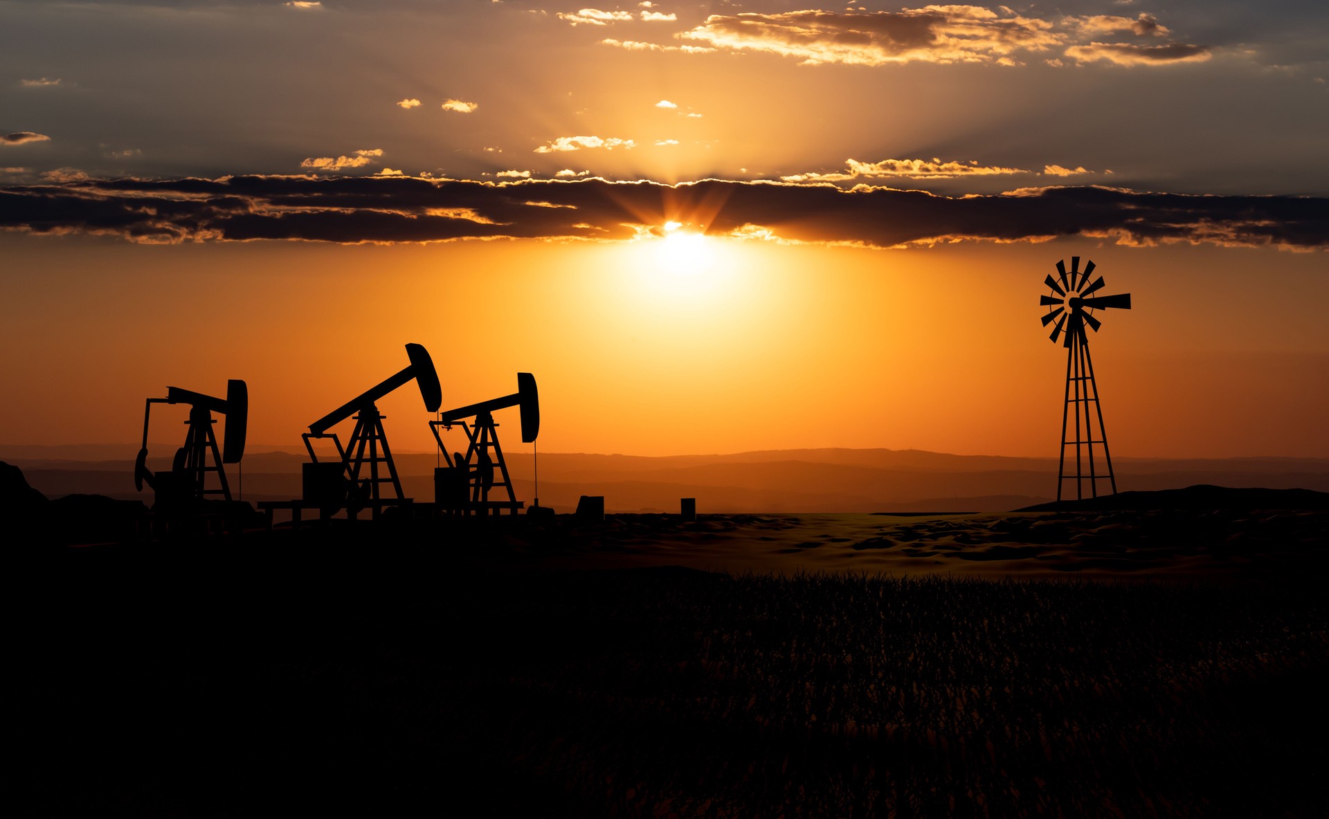 Oil pumps and  wind mill during sunset.